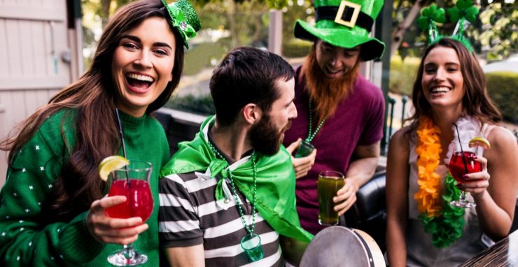 Grupo de quatro amigos celebram festival de St Patrick's Day com trajes e acessórios verdes temáticos