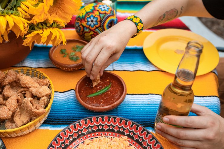 Mesa posta com tecido em amarelo e azul, com pratos da comida mexicana, como chilli e nachos, uma opção para aproveitar rodízios diferentes em Goiânia